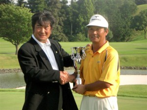 小林旭インビテーショナルの初代チャンピオン・飯合肇（右）に優勝カップを手渡すホスト役の小林旭（左）＝三重・榊原温泉ＧＣで。