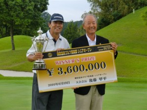 「優勝賞金３６０万円」のチェックと優勝トロフィーを掲げる室田淳（左）とＰＧＡ松井功会長（右）＝三重・榊原温泉ＧＣで