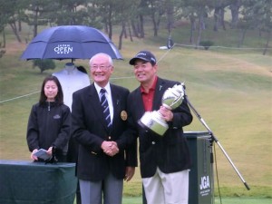 シニア７年目。ようやく日本シニアＯＰのメジャータイトルをとった室田淳（右）。ＪＧＡ安西孝之会長（左）から優勝カップを受けた（広島ＣＣ八本松コース）