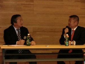 旧知の日本ゴルフジャーナリスト協会理事の三品智加良氏（左）とのトークショーで語る阿部靖彦監督（右）＝都内で